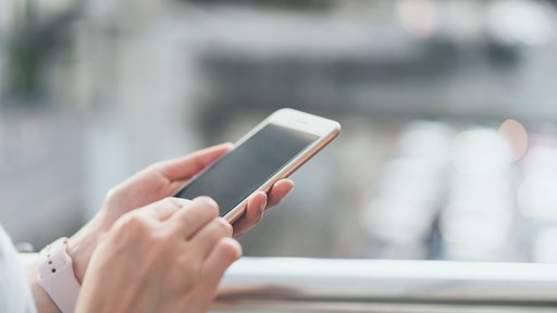 Eine Person hält ein Mobiltelefon in den Händen.