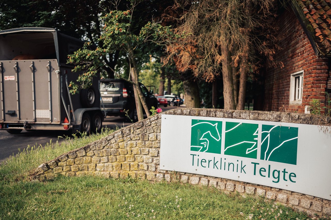 Eine Mauer vor einem Bauernhaus, auf der ein Schild der Tierklinik Telgte angebracht ist