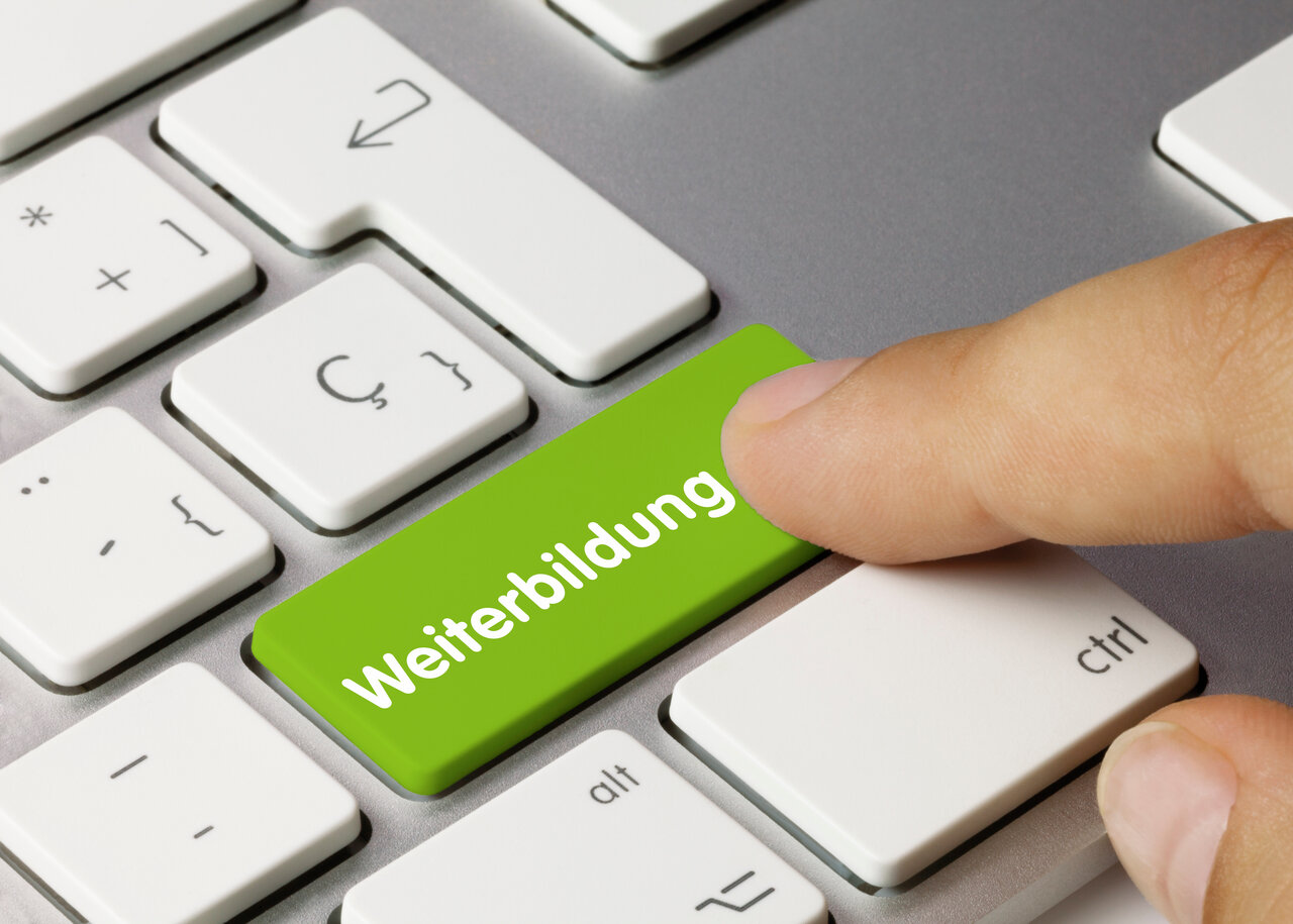 Das Bild zeigt einen Ausschnitt einer Computertastatur. Eine Taste ist grün hinterlegt und trägt die Aufschrift Weiterbildung.